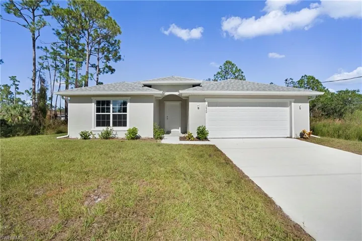 View of front facade featuring a garage and a front lawn