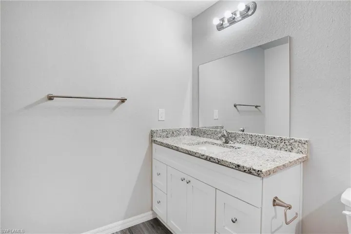 En-suite Bathroom featuring vanity, toilet, and wood-type flooring