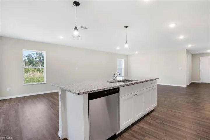 Kitchen with white cabinetry, stainless steel dishwasher, dark hardwood / wood-style floors, decorative light fixtures, and sink