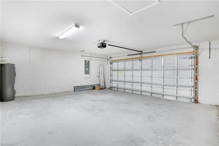 Garage with a garage door opener, electric panel, and water heater