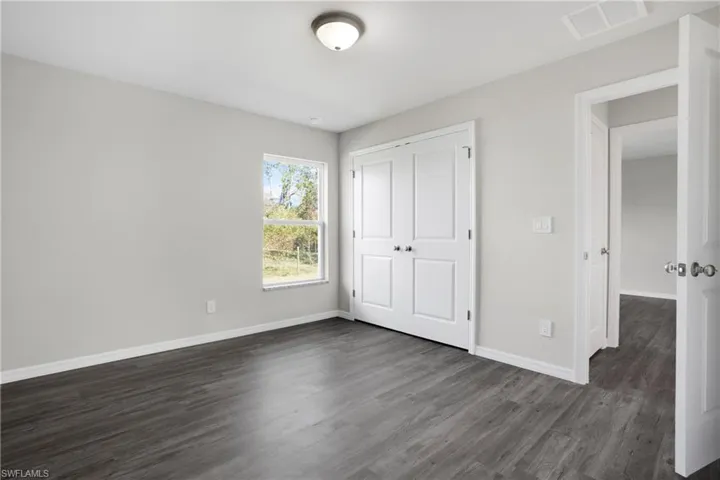 Bedroom with dark wood-type flooring and a closet