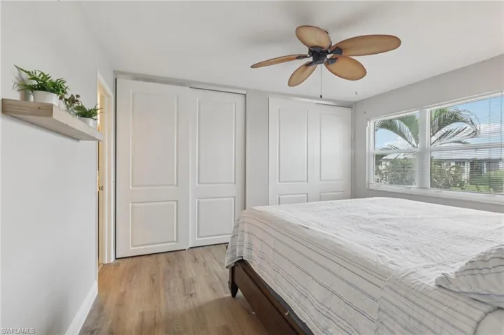 Bedroom with light LVP flooring, multiple closets, and a ceiling fan