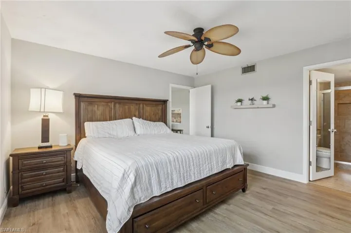 Bedroom featuring light LVP floors, ceiling fan, and ensuite bath