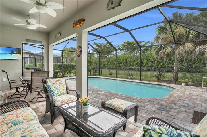 View of pool featuring a patio, ceiling fan, and glass enclosure