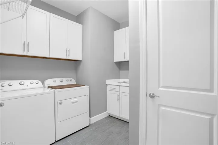Laundry area with washer and clothes dryer, cabinet space, and baseboards