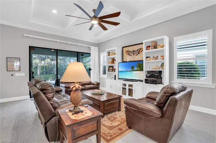 Living area featuring plenty of natural light, a ceiling fan, coffered ceiling, crown molding, and baseboards