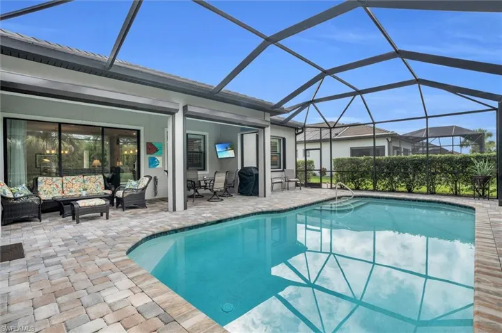 Swimming pool featuring outdoor lounge area, a patio area, and glass enclosure