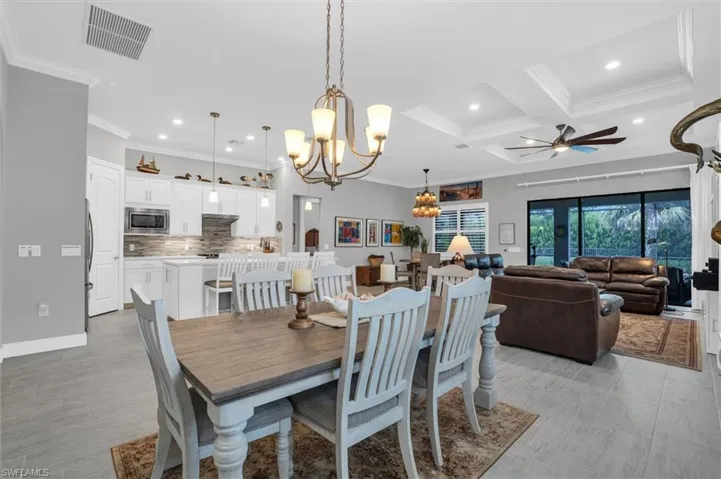 Dining area with a chandelier, crown molding, recessed lighting, a ceiling fan, and coffered ceiling
