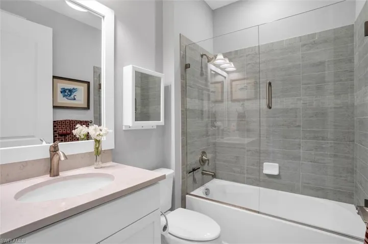 Bathroom featuring vanity, toilet, and shower / bath combination with glass door