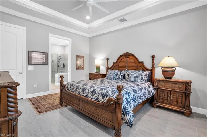 Bedroom featuring recessed lighting, ornamental molding, a raised ceiling, connected bathroom, and a ceiling fan
