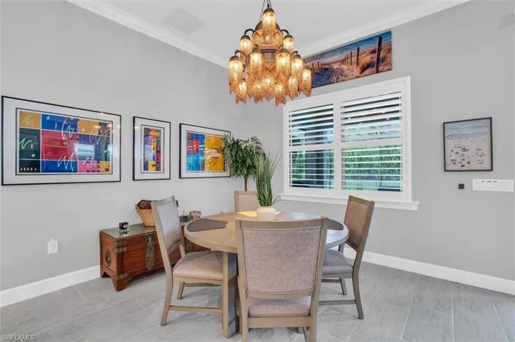 Dining space with a chandelier, baseboards, and ornamental molding