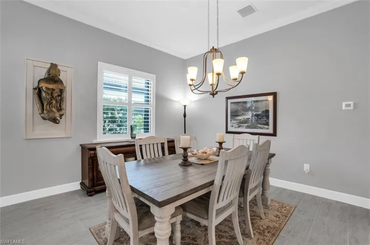 Dining area featuring a chandelier, ornamental molding, baseboards, and light wood-type flooring