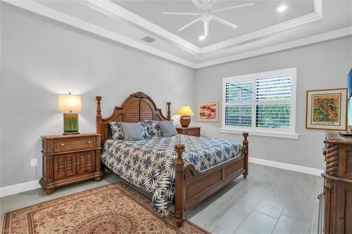 Bedroom with a tray ceiling, crown molding, baseboards, recessed lighting, and a ceiling fan