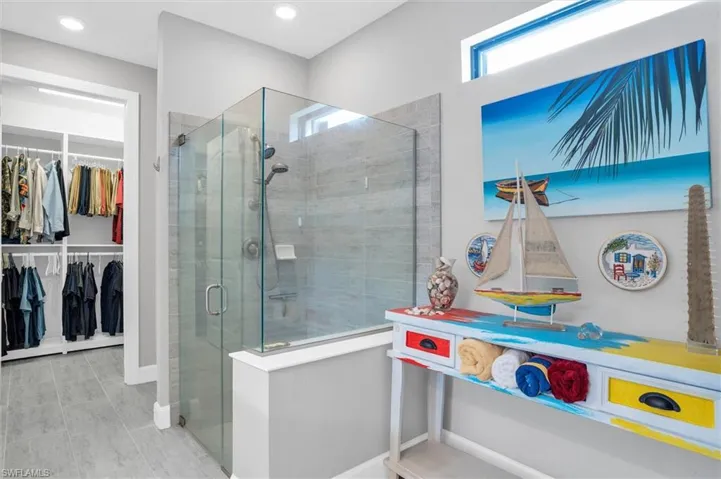 Bathroom featuring a stall shower, a walk in closet, baseboards, and recessed lighting