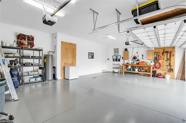 Garage with a workshop area, water heater, and a garage door opener