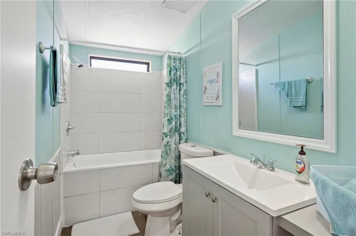 Full bathroom with vanity, a textured ceiling, toilet, and shower / bath combo