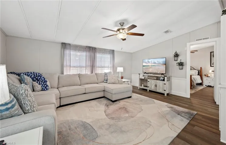 Living room with ceiling fan, dark hardwood / wood-style floors, and vaulted ceiling