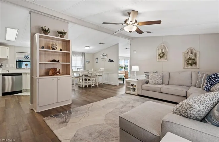 Living room featuring ceiling fan, wood-type flooring, and vaulted ceiling with beams