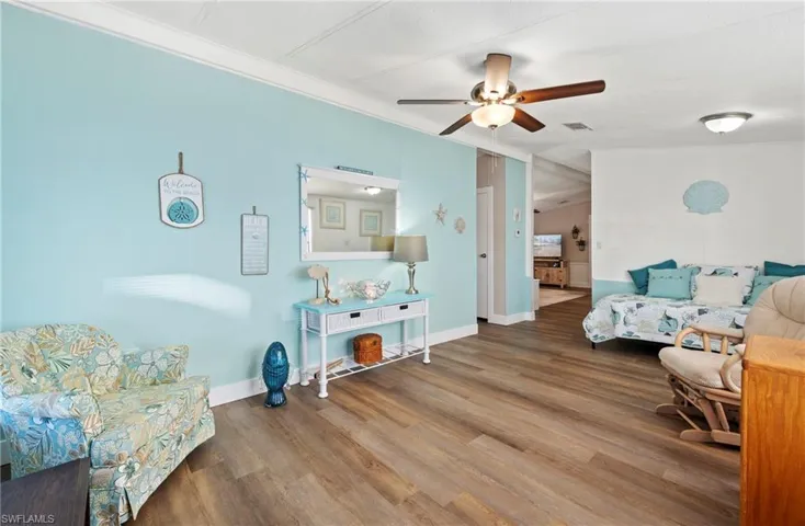 Living room with hardwood / wood-style flooring, crown molding, lofted ceiling, and ceiling fan