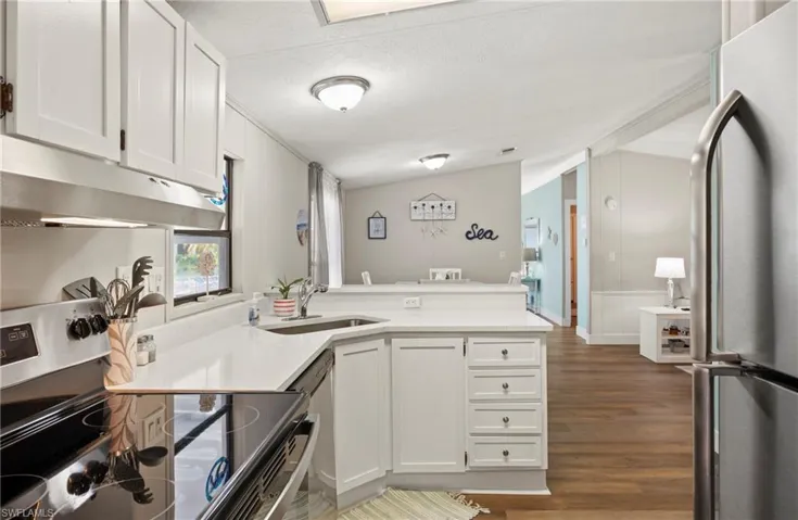 Kitchen featuring appliances with stainless steel finishes, sink, white cabinets, and kitchen peninsula