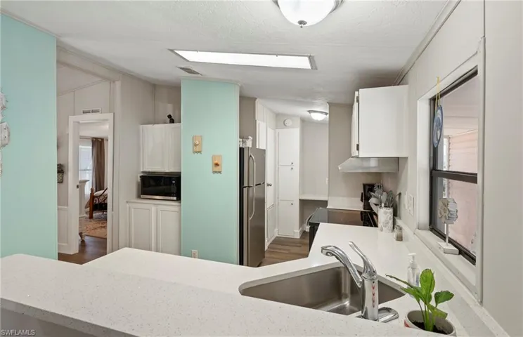 Kitchen featuring stainless steel appliances, a wealth of natural light, sink, and white cabinets