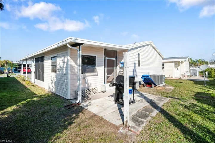 Back of property with cooling unit, a patio, and a lawn