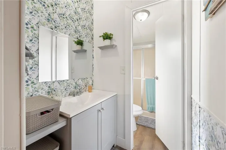 Bathroom with hardwood / wood-style floors, vanity, toilet, and a shower with shower door