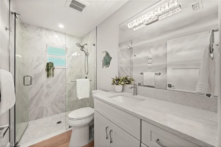 A beautifully updated guest bath featuring a frameless glass shower, marble-look tile, and a sleek quartz vanity, refined, bright, and spa-inspired.