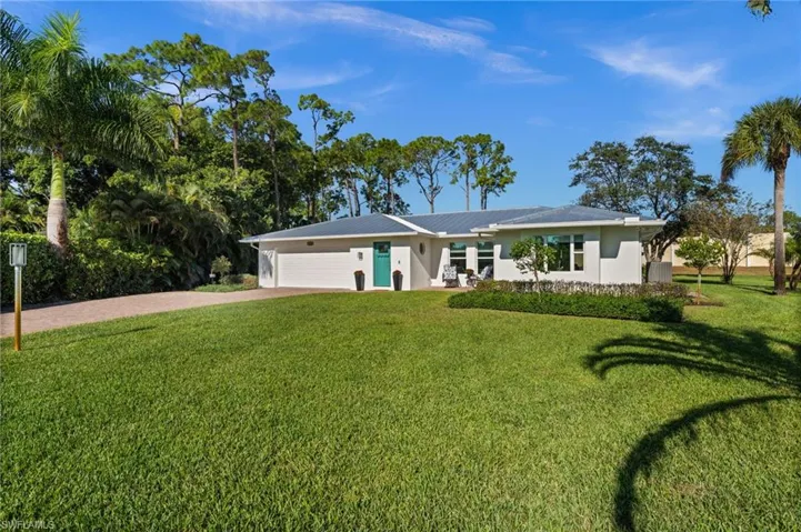 A private North Naples retreat, set on an expansive .34-acre cul-de-sac lot with lush greenery, a modern metal roofline, and timeless coastal architecture.