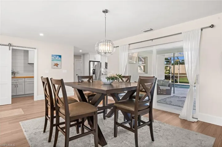 A refined dining space where natural light pours in, complementing clean lines, elegant fixtures, and seamless flow to the poolside lanai.