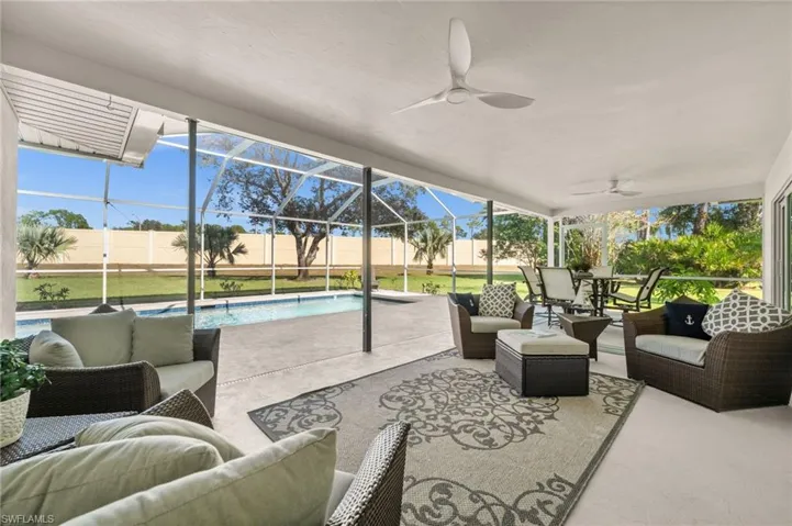 An expansive screened lanai designed for year-round enjoyment, with multiple lounging zones, dining space, and serene views of the pool and greenscape.