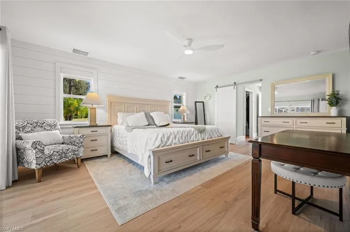 Spacious and beautifully curated, the primary bedroom offers refined comfort with layered textures, dual windows, and an elegant barn-door entry to the ensuite and closet.
