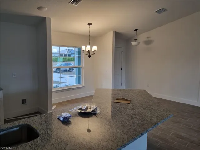Kitchen with dark stone counters, wood finish floors, and a chandelier