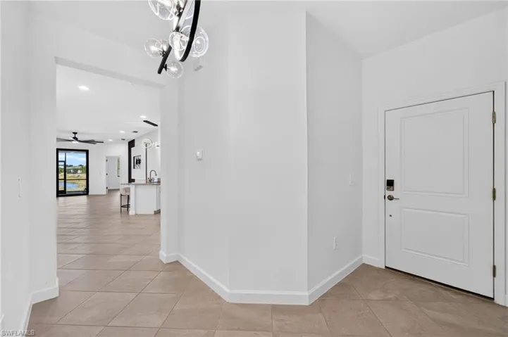 Foyer featuring neutral-tone tile flooring, a multi-globe chandelier with a black finish, and a solid-core paneled entry door