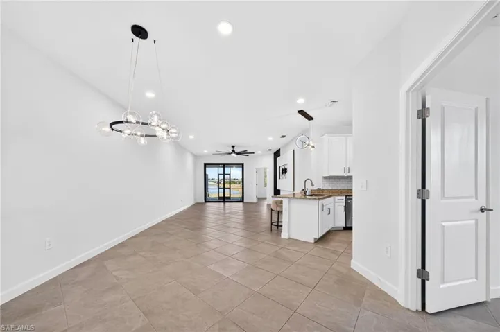 Open floor plan featuring oversized tile flooring, a contemporary circular chandelier, recessed lighting, and a kitchen island with stone countertops