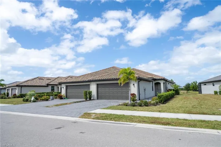 Exterior featuring a tile roof, light-toned stucco facade, paved driveway, and a two-car garage