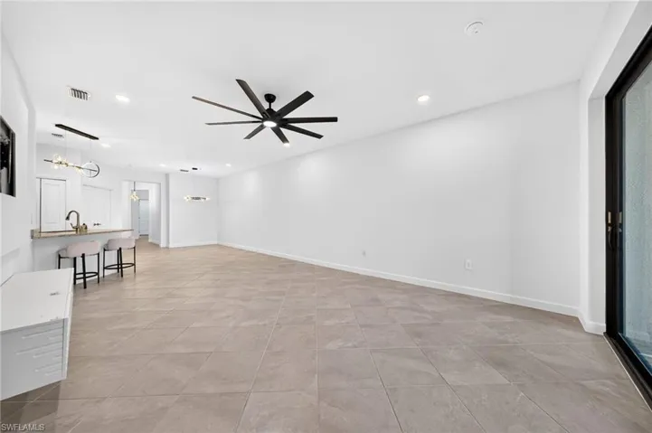 Open floor plan featuring large-format diagonal floor tiles, multi-blade ceiling fan, recessed lighting, and sliding glass doors