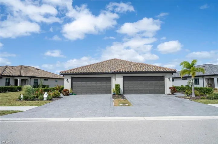 Stucco exterior featuring a dual-garage configuration with paneled doors and a paved driveway leading to a tile roof