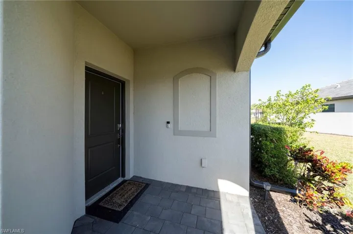 Covered entryway featuring a paver patio, stucco exterior wall with arched architectural detailing, and a solid-panel front door