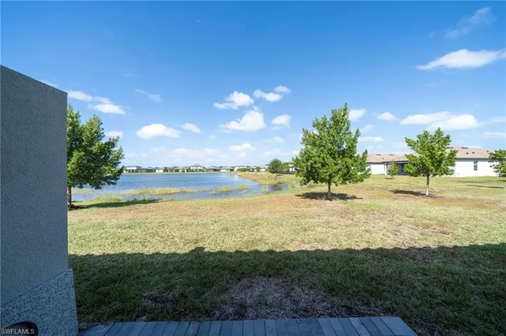 Backyard featuring a paved patio, expansive lawn, mature trees, and direct water frontage