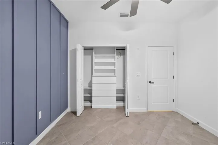Accent wall with vertical paneling, diagonal-set ceramic tile flooring, built-in closet shelving and drawer unit, and a two-panel interior door