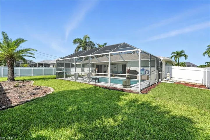 View of swimming pool with grilling area, a fenced backyard, glass enclosure, and a patio area