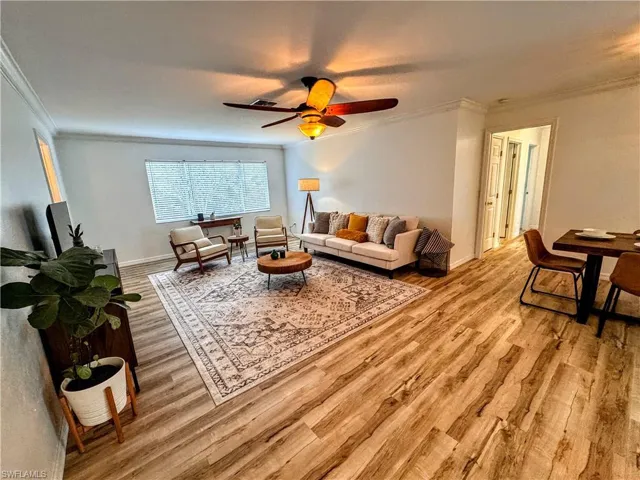 Living area featuring crown molding, baseboards, light wood finished floors, and ceiling fan