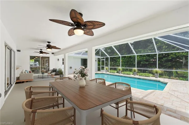 Virtually StagedView of pool featuring glass enclosure, ceiling fan, a patio, and an outdoor living space