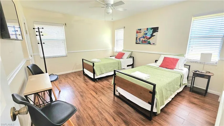 Bedroom with multiple windows, ceiling fan, and dark hardwood / wood-style flooring