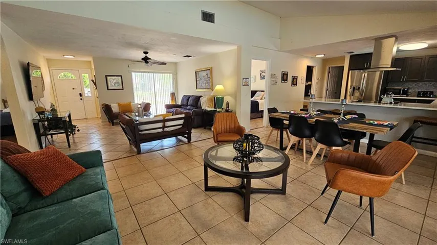 Living room featuring ceiling fan, vaulted ceiling, and light tile patterned floors