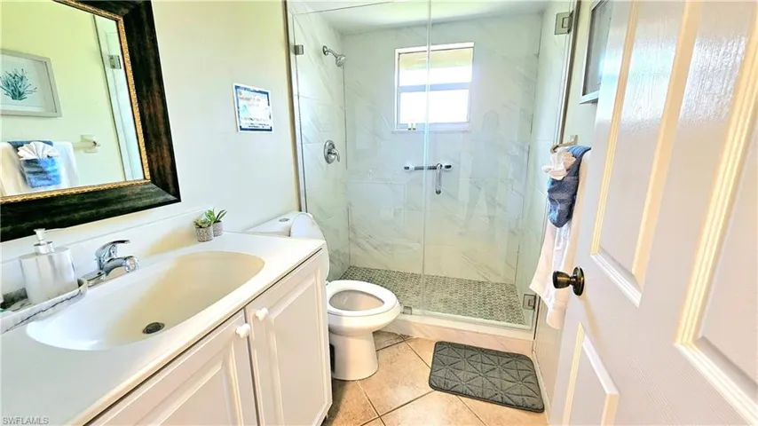 Bathroom with tile patterned flooring, vanity, a shower with shower door, and toilet
