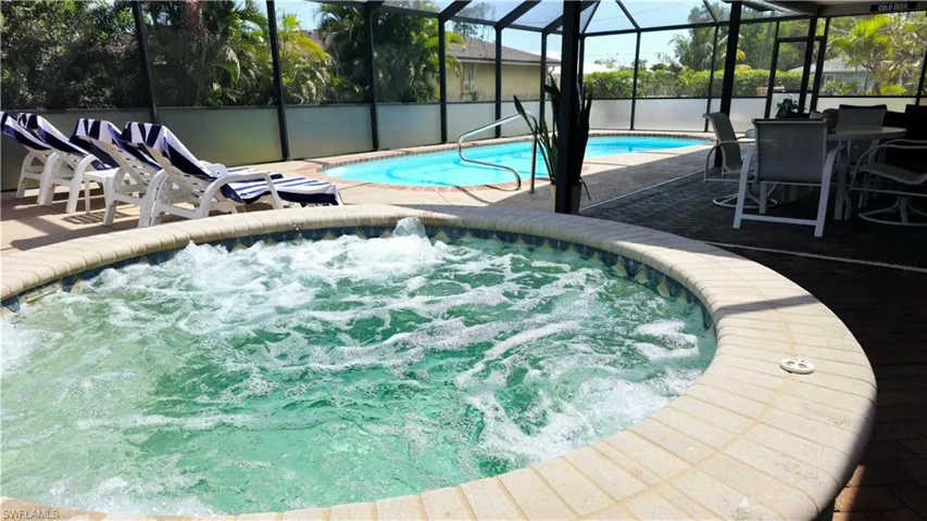 View of pool featuring a lanai, a patio area, and an in ground hot tub
