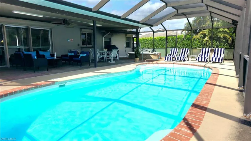 View of pool featuring ceiling fan, outdoor lounge area, glass enclosure, and a patio