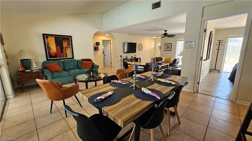 Dining room featuring ceiling fan, vaulted ceiling, and light tile patterned floors
